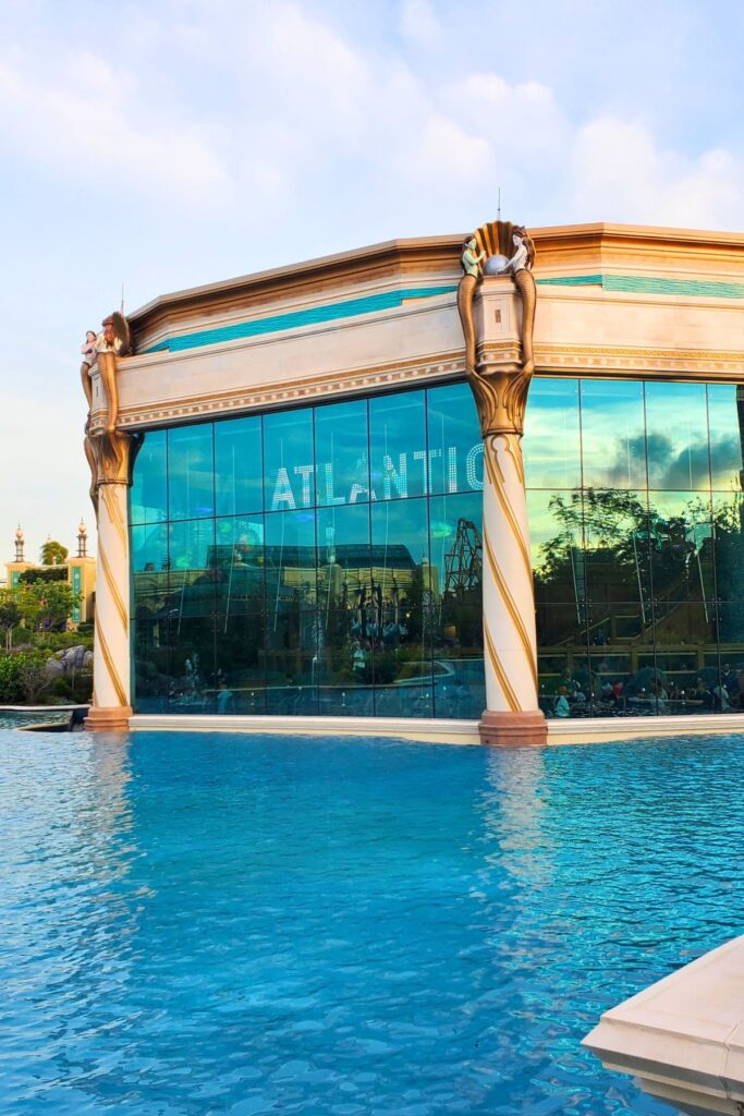 Front view of Atlantic restaurant in Epic Universe by a pool of bright blue water