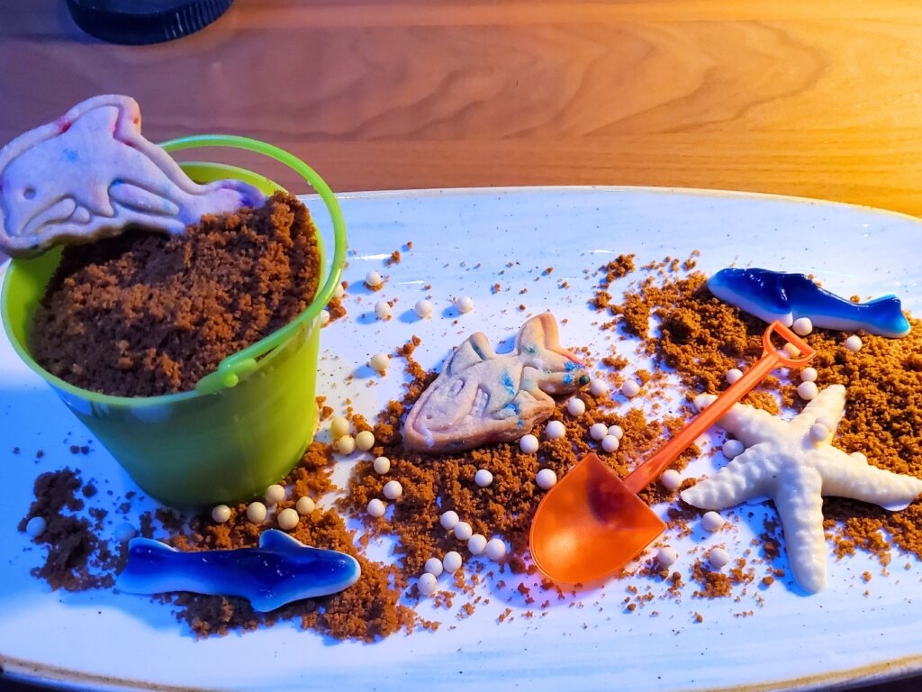 snickerdoodle dessert in a small sand pail with a mini shovel to eat with shark and dolphin cookies and gummies