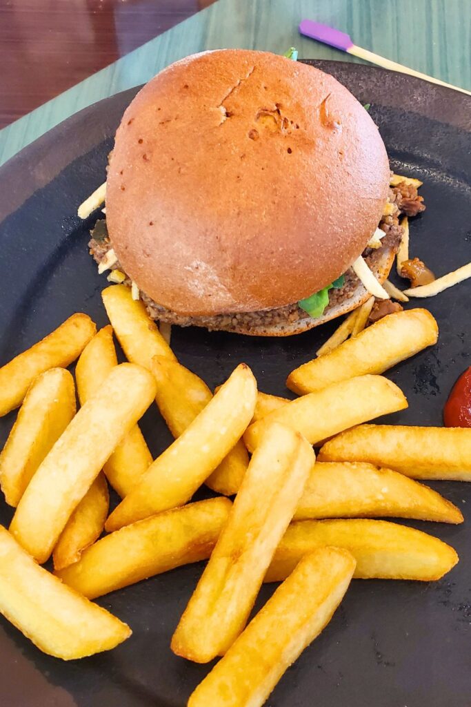 sloppy joe and brisket sandwich on a gluten free bun with fries on a black plate